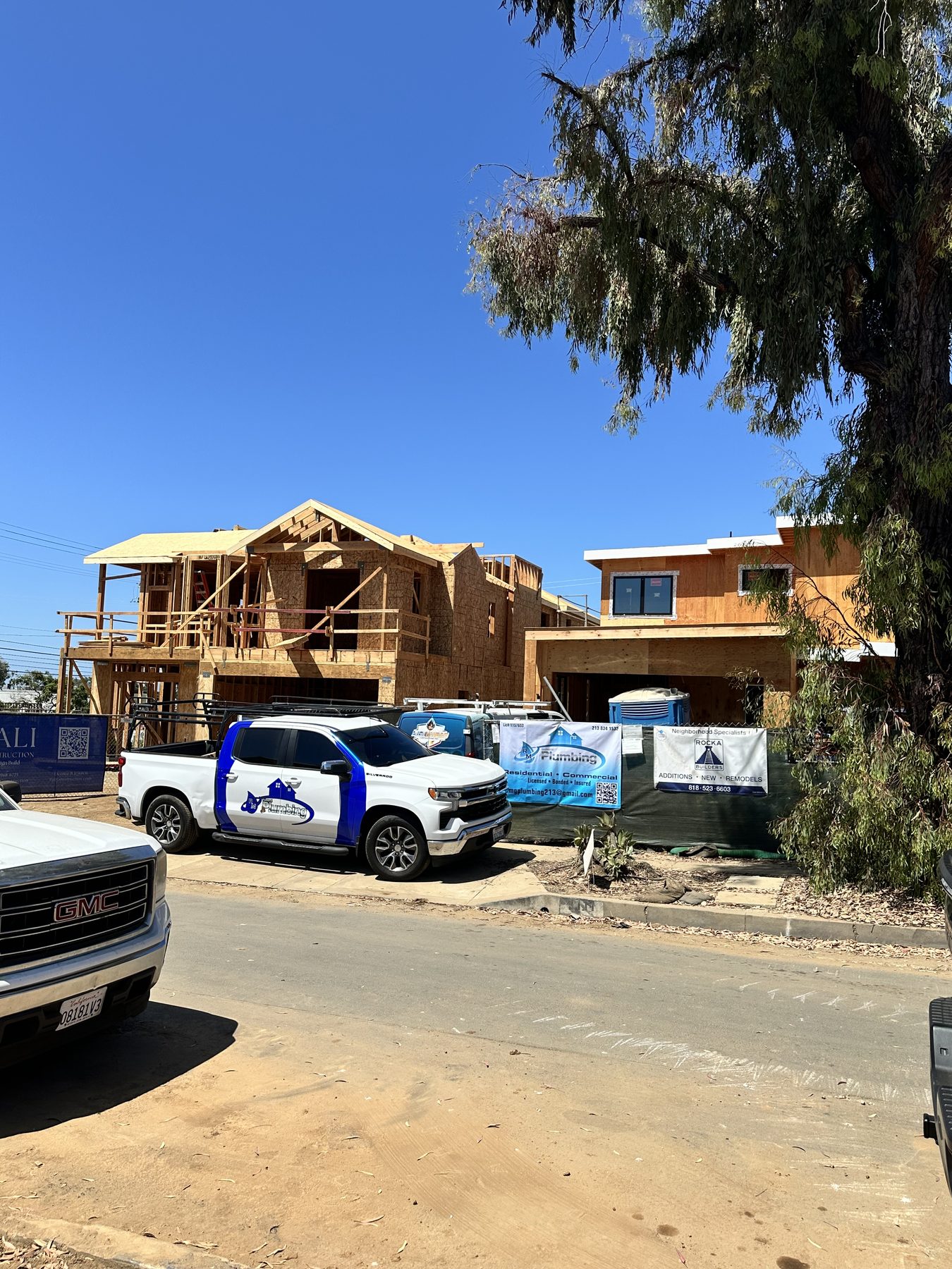 RAMG Plumbing branded work truck and company banner at an active residential construction site